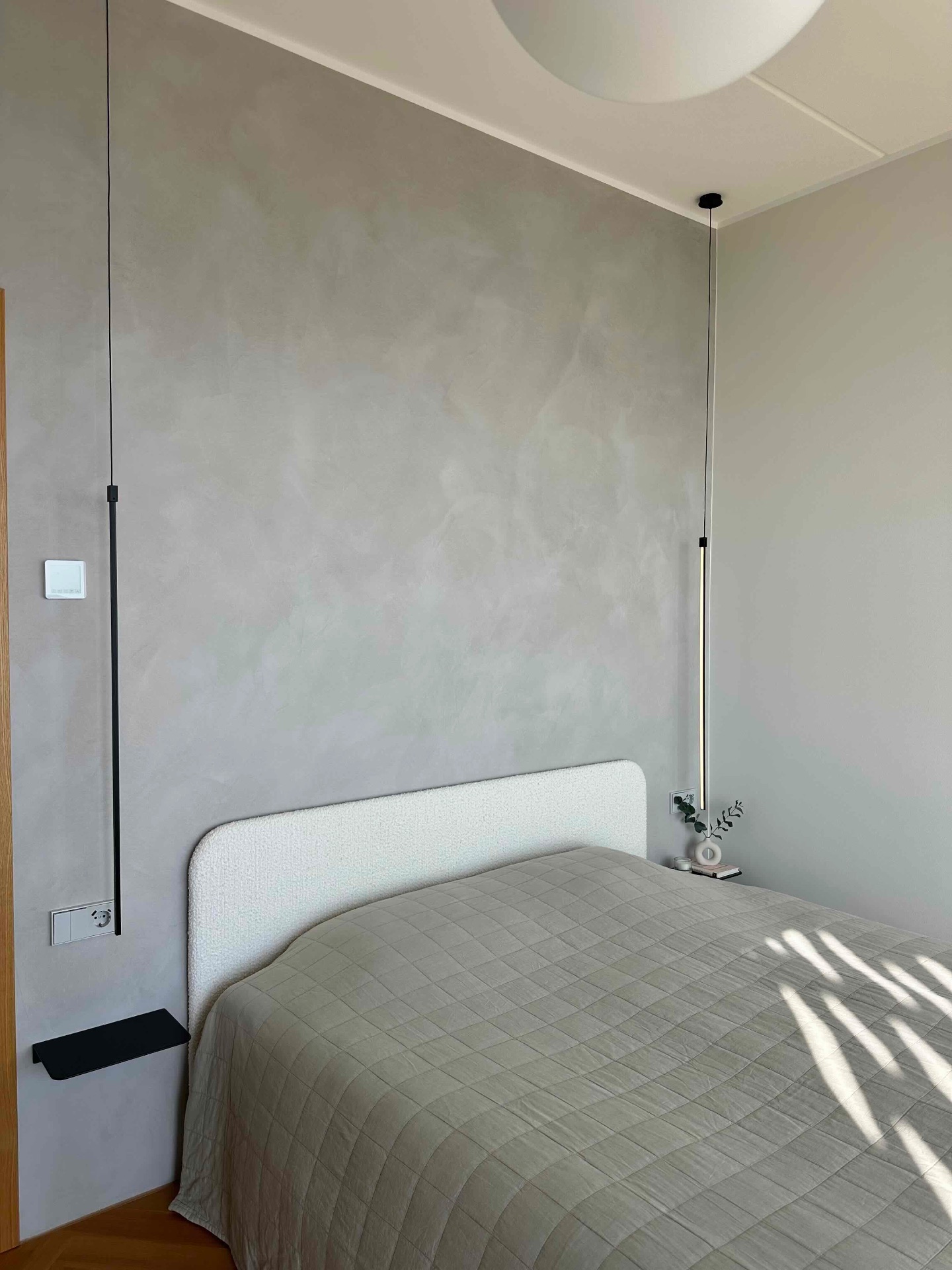 The bedroom in daylight, plain walls and quiet light