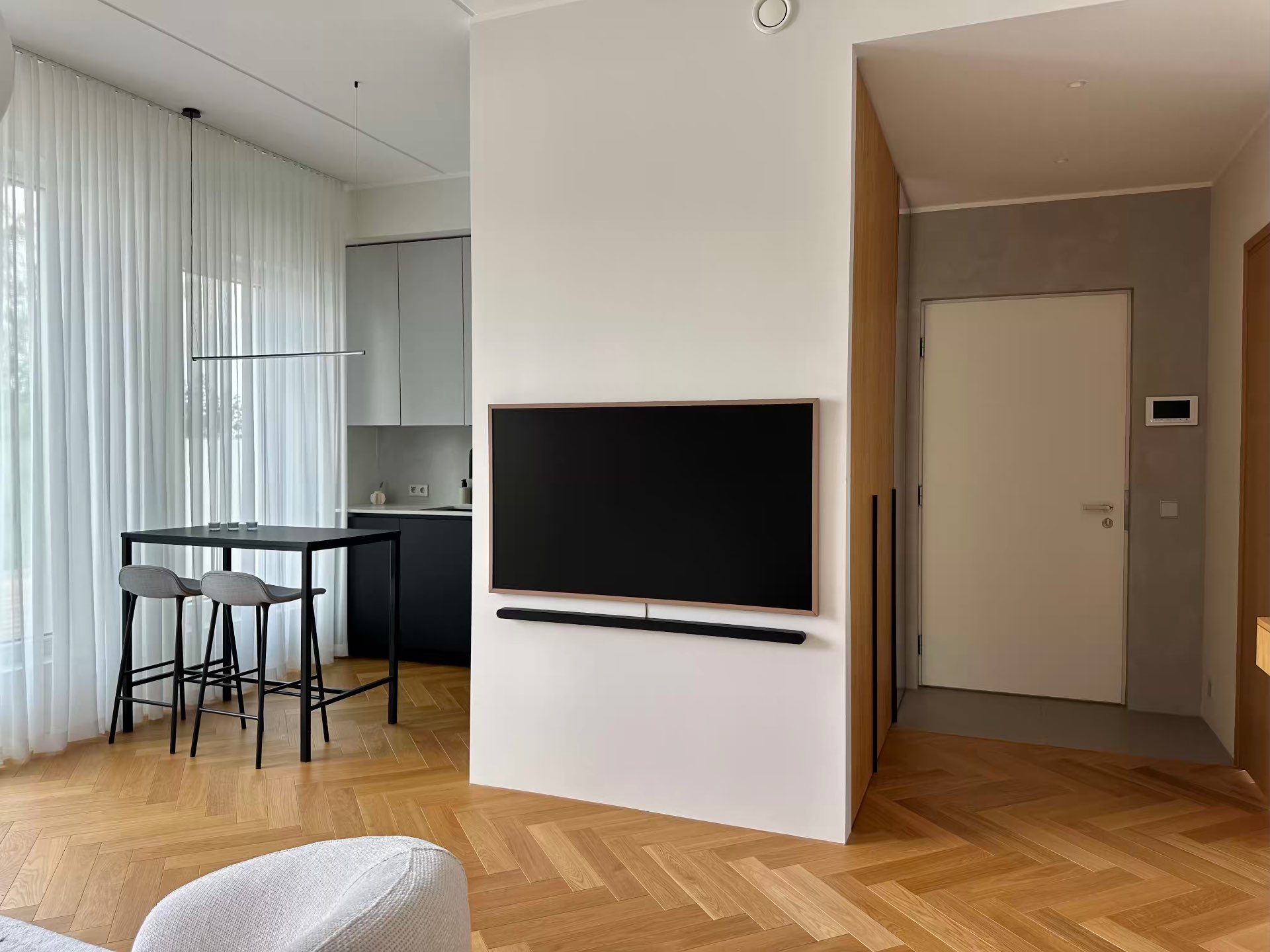The high table with bar stools and the television wall, kitchen behind