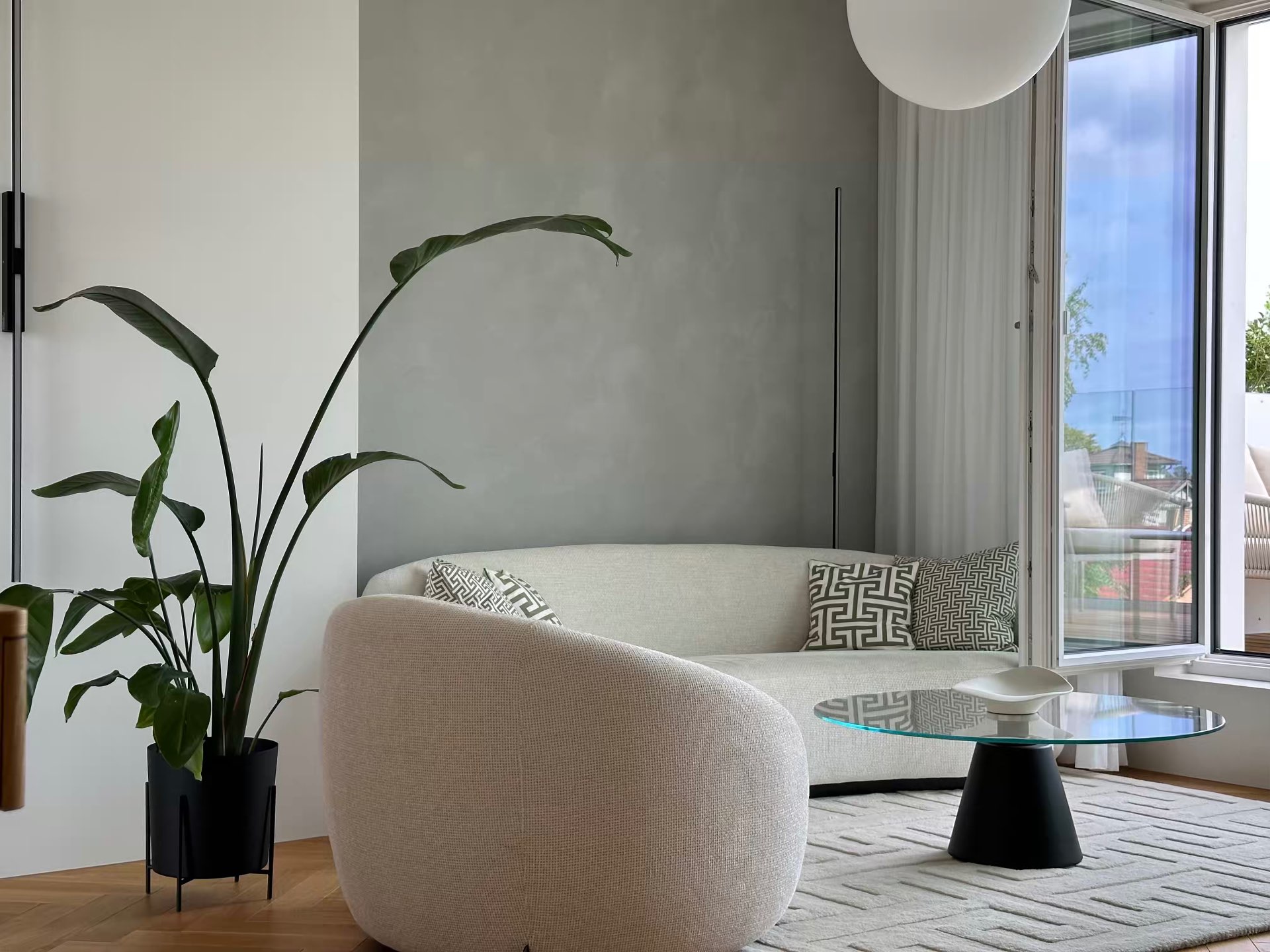 The living room sofa by the window, large plant beside it