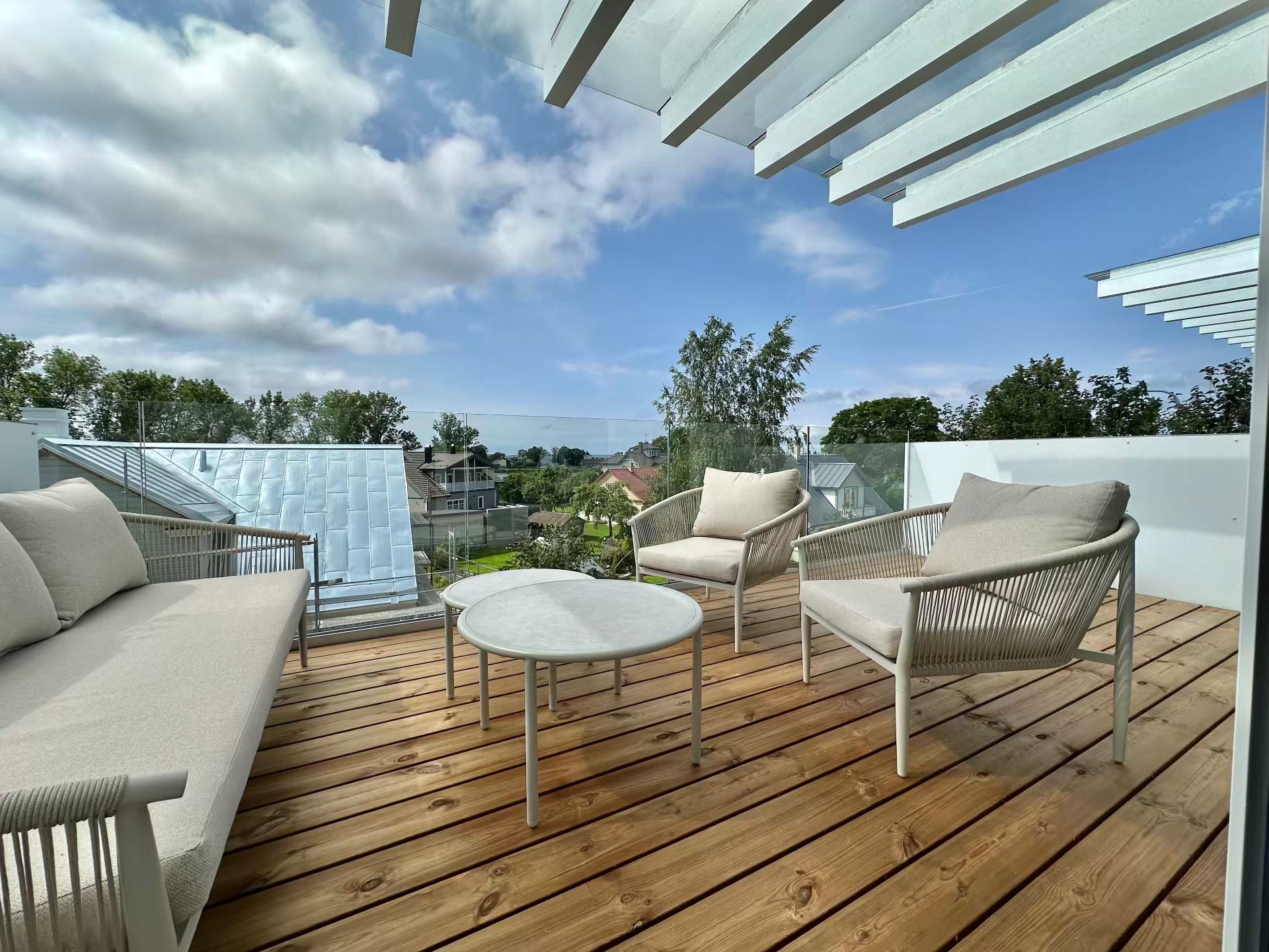 The 15m² west terrace with sofa, chairs and table under the pergola beams