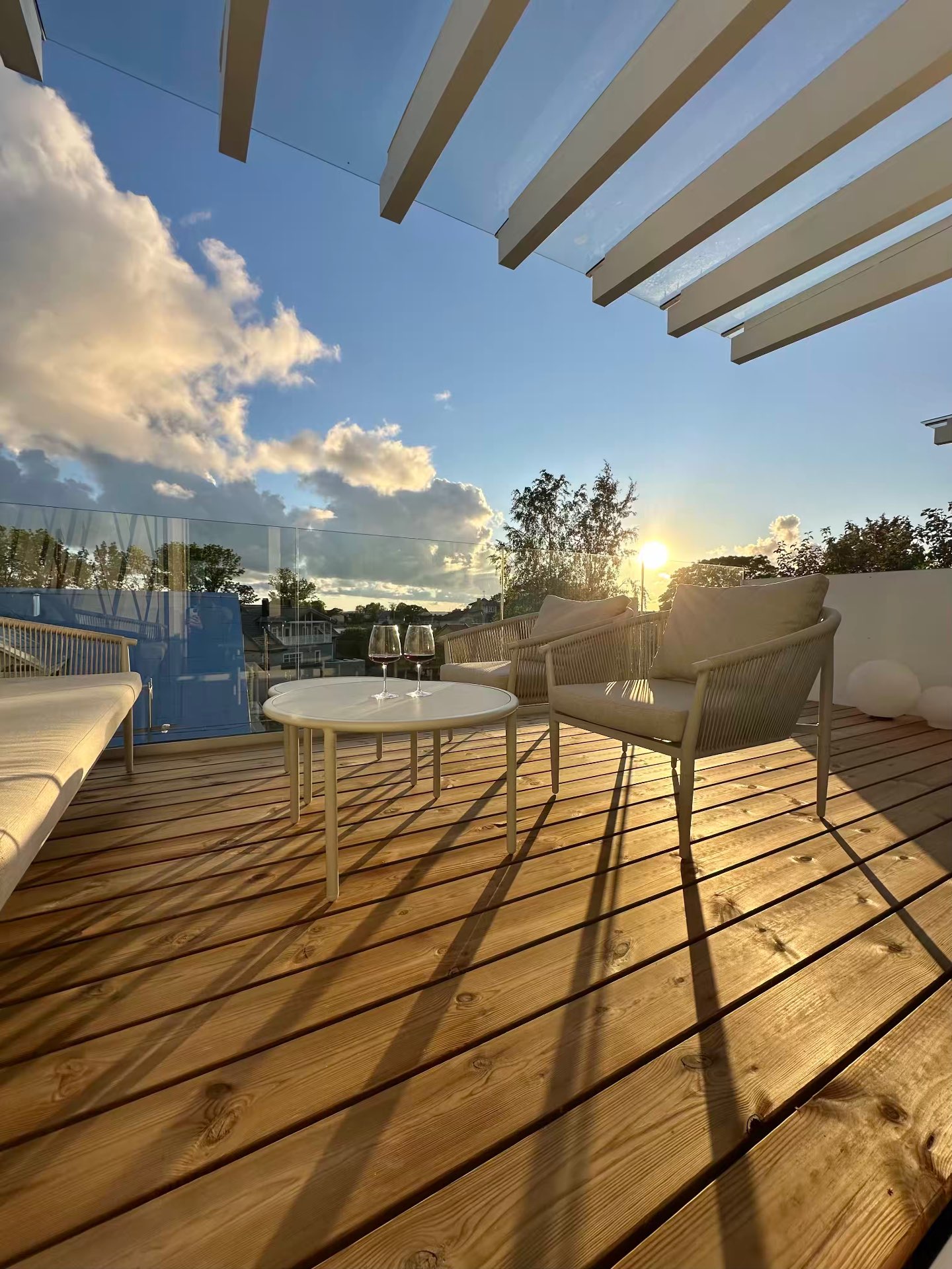 The 15m² west terrace at golden hour, two glasses on the table